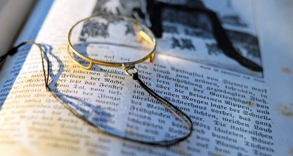 Canva - Close-up Photography of Gray Framed Magnifying Glass on Opened Book